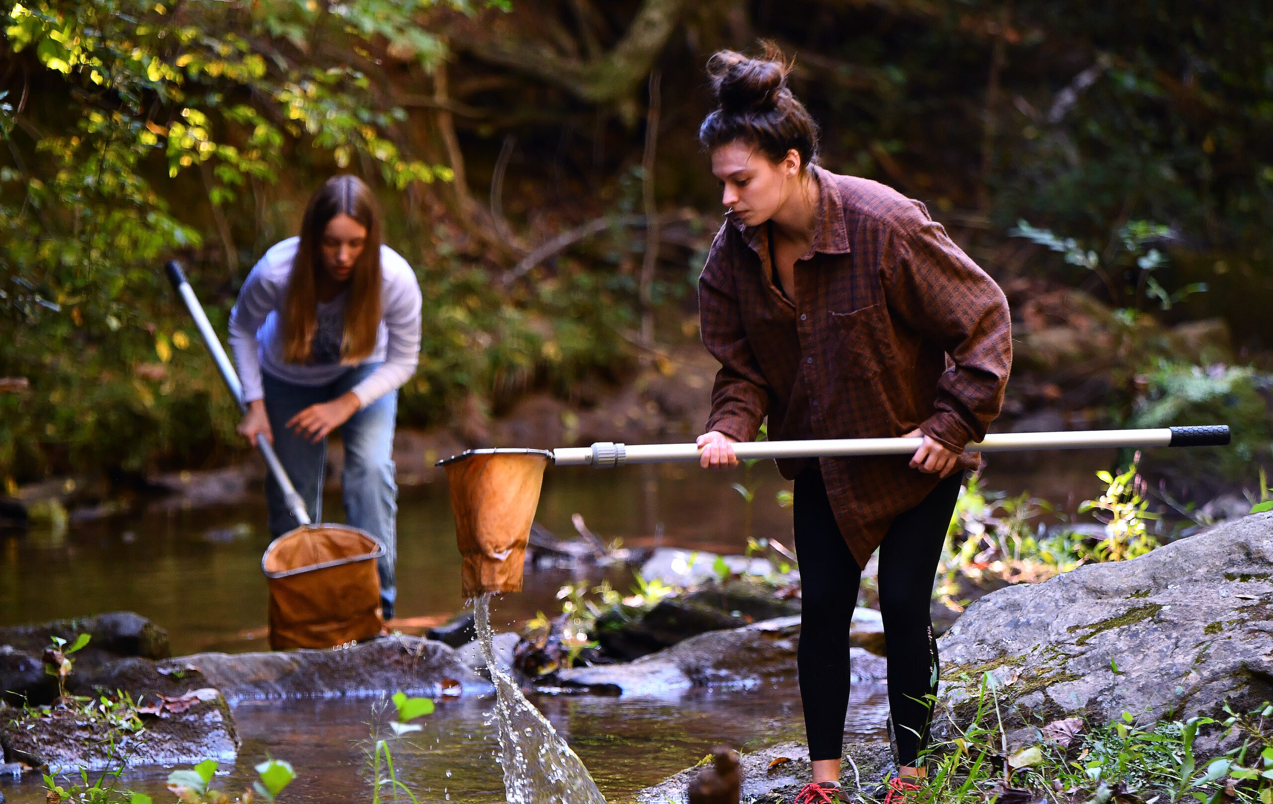 Two students in a creek with nets
