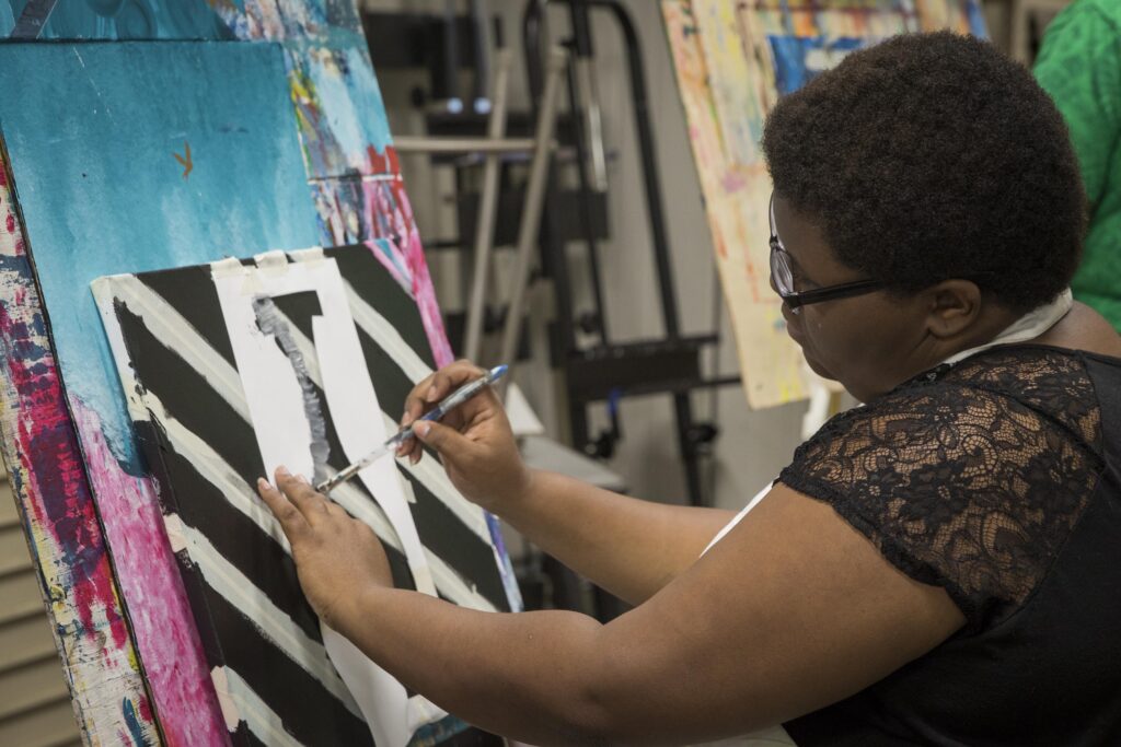 A student paints on a canvas