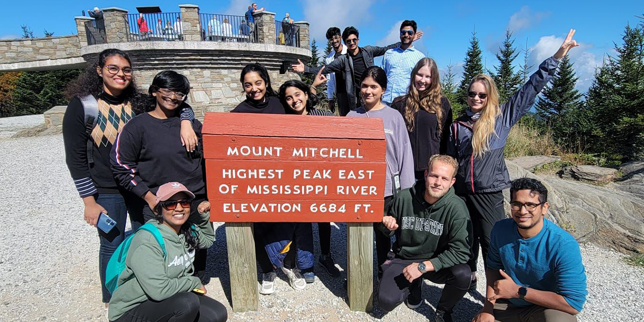 A group of students pose near a sign