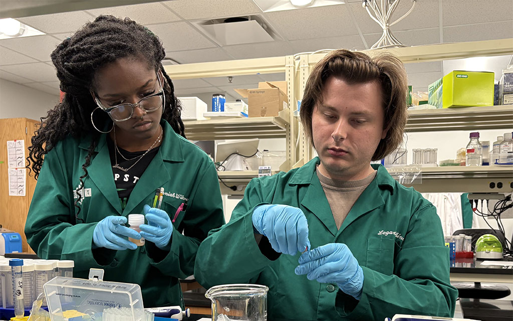 two students in green lab coats
