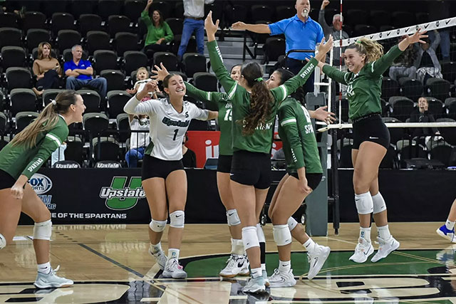 a group of women in volleyball uniforms celebrating