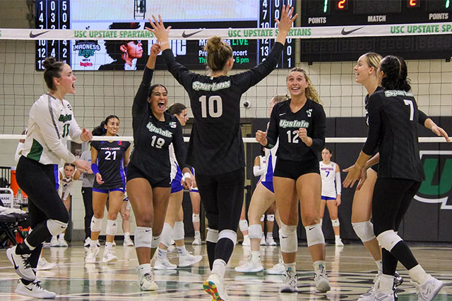 a group of women in volleyball uniforms celebrating