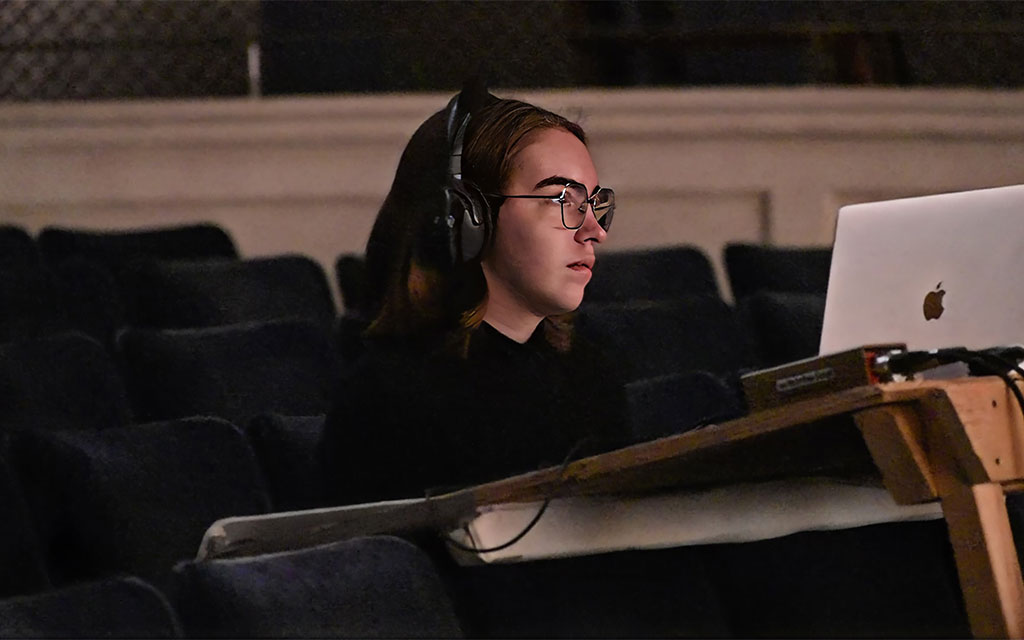 Avery Beaton sitting in front of a laptop with headphones on