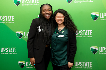 two students and a green Upstate backdrop