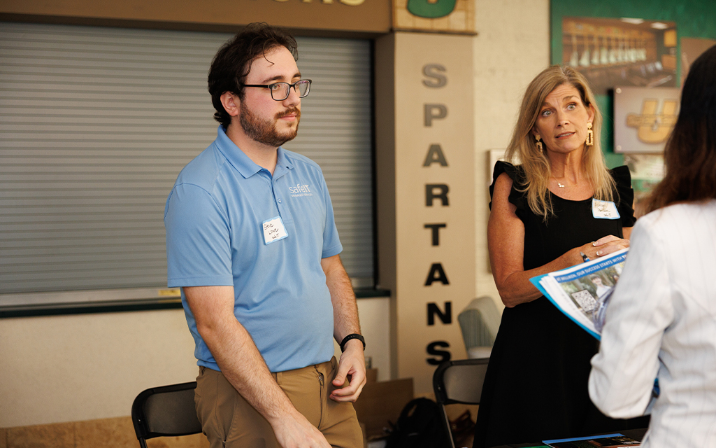 two Upstate alumni stand behind a table