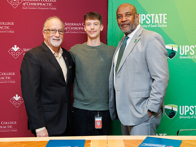 Chancellor Bennie L. Harris stands with Jack Bourla, D.C., A.C.P., President stand with Sherman College student