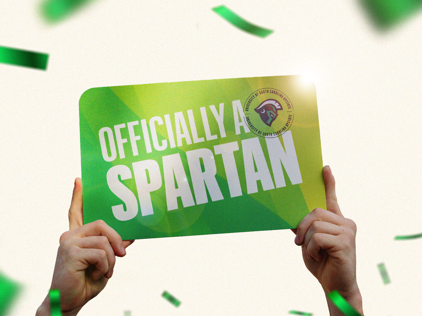 Hand holding a sign high in the air that reads "officially a spartan"