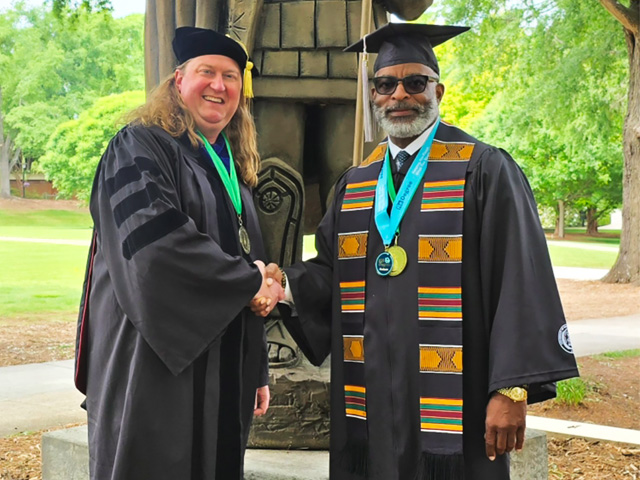 Harold Mitchell shakes hands with Colby King.